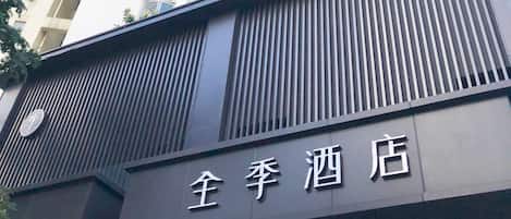 A high-rise hotel building with a modern facade, multiple balconies, and a sign indicating it is a hotel.