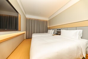 A hotel room with a large bed, a bedside table, a mirror, and a window with curtains.