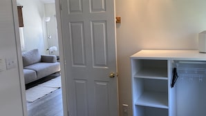 A bedroom with a bed, a wardrobe, and a door leading to another room. - Hardy’s cute and cozy beach cottage  (Pointe-du-Chene)