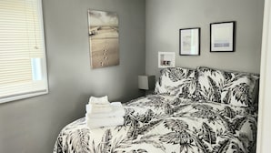 A bedroom with a bed, a wall-mounted picture, and a bedside table. - Hardy’s cute and cozy beach cottage  (Pointe-du-Chene)