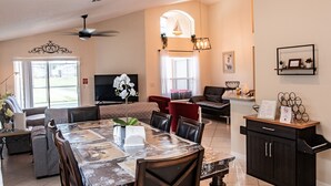 A spacious living area with a dining table, chairs, sofas, and a television. - Relaxing 4BR + 3Bath Villa Sleeps 10, with FREE heated pool!  (Kissimmee)