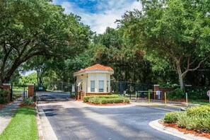 Un ingresso recintato con un piccolo edificio, immerso nel verde e circondato da un prato curato.