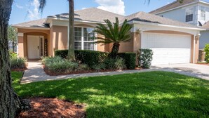 A residential house with a front yard, a driveway, and a garage. - Relaxing 4BR + 3Bath Villa Sleeps 10, with FREE heated pool!  (Kissimmee)