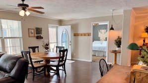A spacious living room with a dining area, a leather sofa, a wooden coffee table, and a ceiling fan. - Natures Crest Retreat, Hocking Hills (Logan)