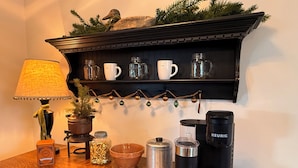 A kitchen counter with a coffee maker, a lamp, a shelf with jars and a mug, and a decorative plant. - Natures Crest Retreat, Hocking Hills (Logan)