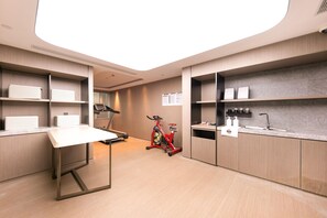 A modern kitchen with a dining table, a red stationary bike, and a small island with a sink. - Ji Hotel (Shanghai)