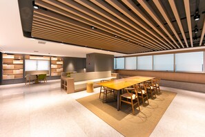 A modern interior with a long wooden table, multiple chairs, a sofa, and built-in bookshelves. - Ji Hotel (Shanghai)