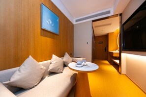 A modern hotel room with a sofa, a small round table, and a television. - Ji Hotel (Shanghai)