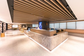 A modern reception area with a marble counter, wooden slatted ceiling, and large windows. - Ji Hotel (Shanghai)