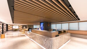 A modern reception area with a marble counter, wooden slatted ceiling, and large windows.