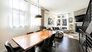 A modern living room with a wooden dining table, a sofa, and a fireplace. - Modern 3 Bedroom in Queen Anne with Rooftop + AC (Seattle)