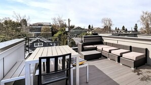 A rooftop deck with a table and chairs, a sofa, and a small table with a lamp. - Modern 3 Bedroom in Queen Anne with Rooftop + AC (Seattle)
