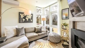 A living room with a sofa, a round ottoman, a fireplace, and a world map on the wall. - Modern 3 Bedroom in Queen Anne with Rooftop + AC (Seattle)