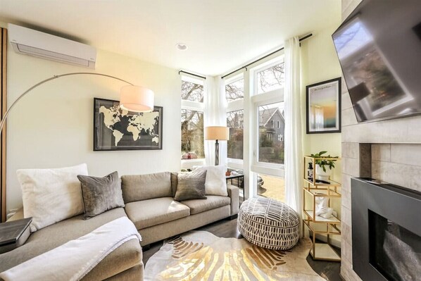 A living room with a sofa, a round ottoman, a fireplace, and a world map on the wall.