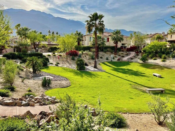 A residential area with houses, a well-maintained lawn, and a mountain backdrop.