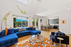 A modern living room with a sectional sofa, a glass coffee table, and a view of the outdoors.