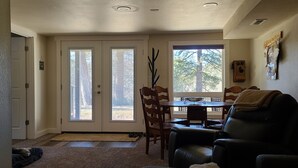 A room with a dining area, a sofa, and a door leading to an outdoor space.