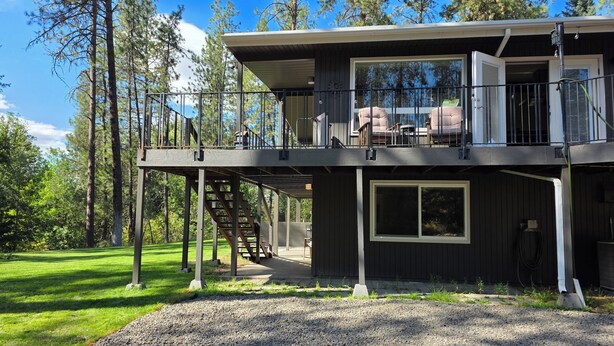 A two-story cabin with a balcony, a staircase, and a large window.