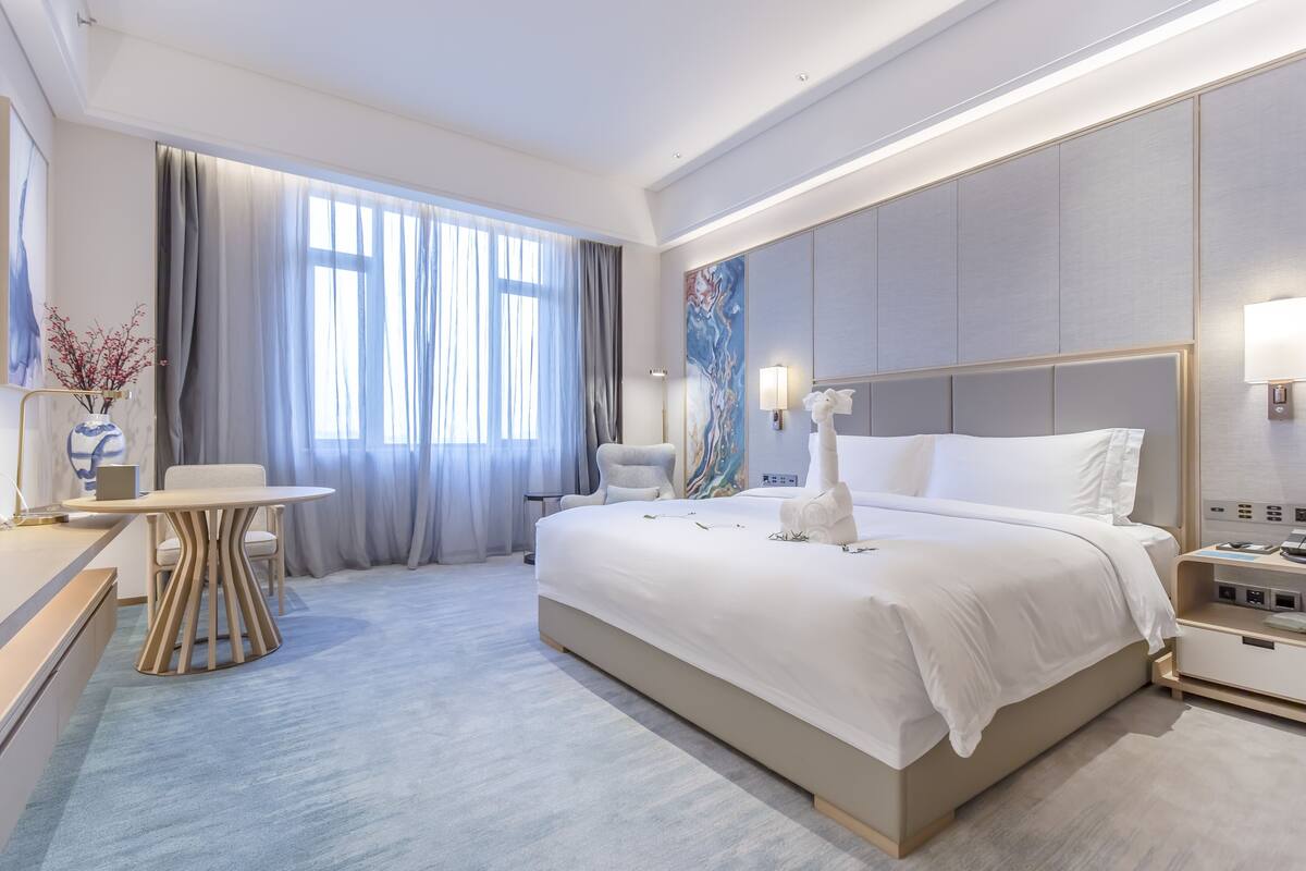 Een moderne hotelkamer met een groot bed, een bureau en een stoel.