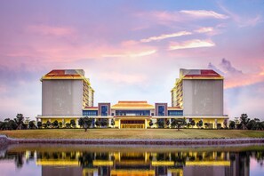 Een groot, modern gebouw met een symmetrische gevel, een centrale ingang en een spiegelbeeld in stil water.