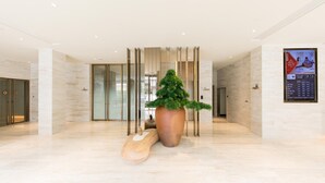 A modern lobby with a large potted plant, a wooden sculpture, and a digital display. - Ji Hotel (Shanghai)