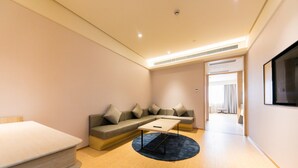 A modern living room with a sofa, a coffee table, and a TV mounted on the wall. - Ji Hotel (Shanghai)