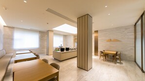 A modern hotel lobby with a central island, seating areas, and a large window providing natural light. - Ji Hotel (Shanghai)