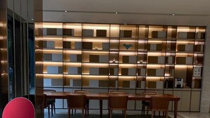 A modern interior with a dining area, a red chair, a wall with shelves, and a ceiling with recessed lighting. - Ji Hotel (Shanghai)