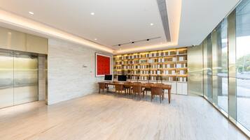 A modern interior with a wooden table and chairs, a large bookshelf, and a view through a glass wall.