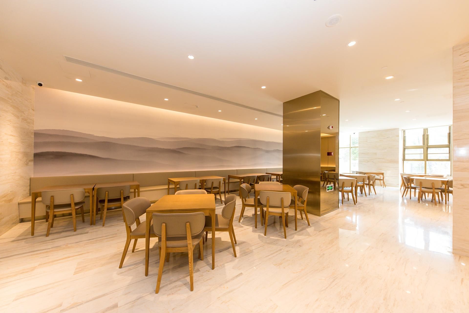 Um restaurante moderno com mesas e cadeiras de madeira, um grande mural na parede e piso de mármore polido.
