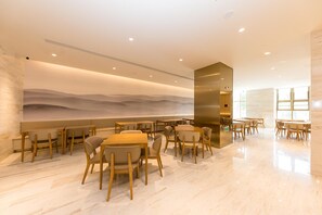 A modern restaurant with wooden tables and chairs, a large mural on the wall, and a polished marble floor. - Ji Hotel (Nanjing)