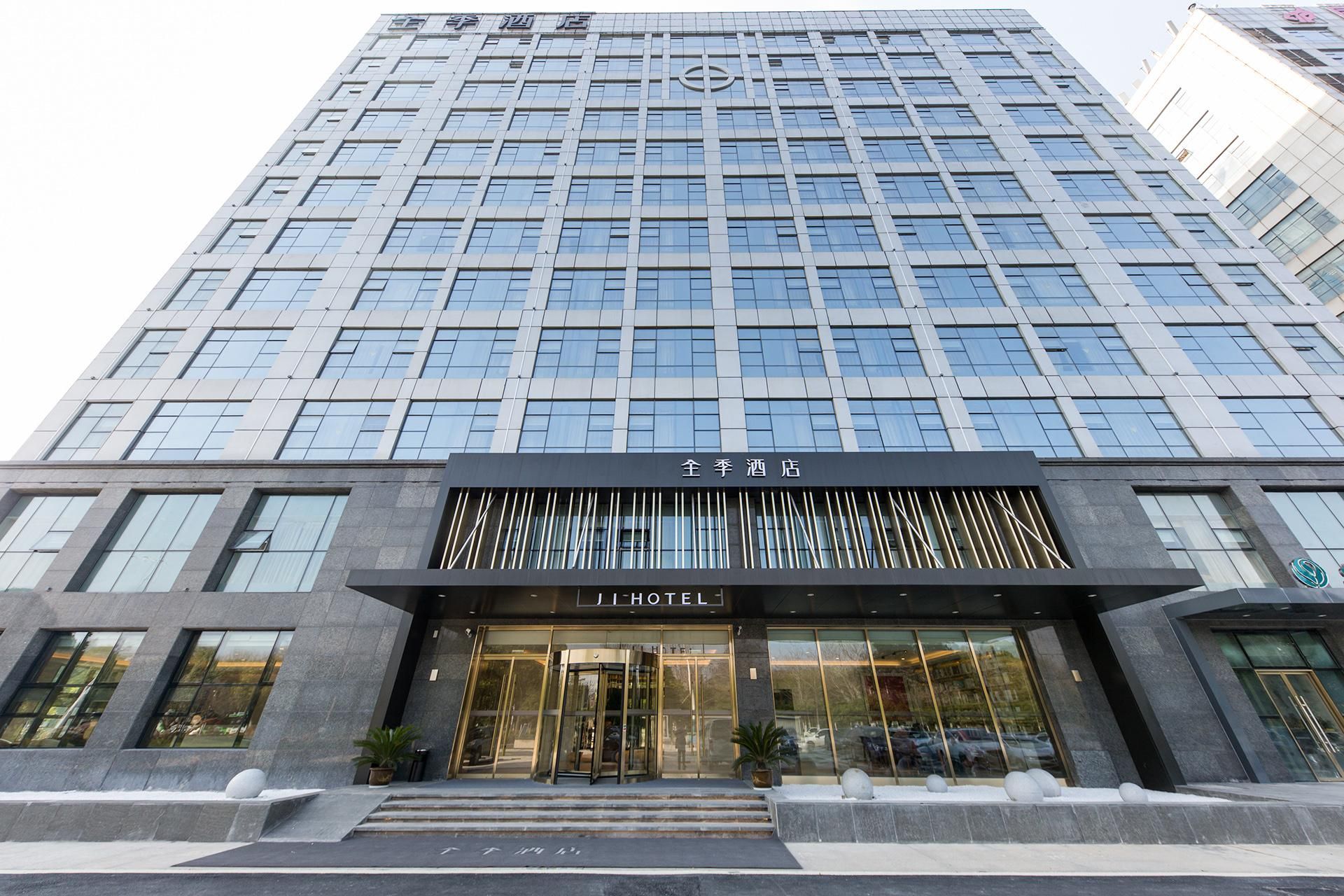 Een modern hotelgebouw met een glazen gevel, een opvallende ingang met een bord en een symmetrisch ontwerp.
