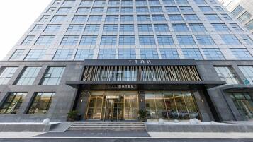 Ein modernes Hotelgebäude mit Glasfassade, einem markanten Eingang mit einem Schild und einem symmetrischen Design.