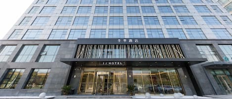 Un moderno edificio de hotel con fachada de vidrio, una entrada destacada con un letrero y un diseño simétrico.