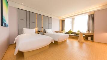 A hotel room with two beds, a sofa, a small table, and a large window with curtains.