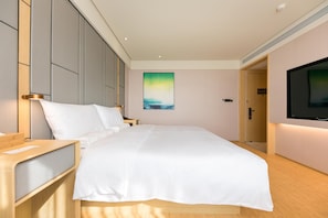 A hotel room with a bed, bedside tables, a TV, and a painting on the wall. - Ji Hotel (Nanjing)