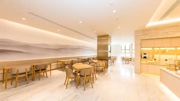 A modern restaurant with wooden tables and chairs, a bar area, and a view of the desert.