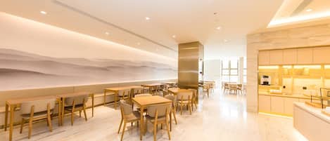 Un restaurant moderne avec des tables et des chaises en bois, un bar et une vue sur le désert.
