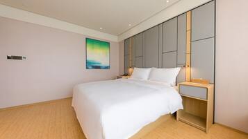 Ein modernes Hotelzimmer mit einem großen Bett, einem Nachttisch, einer Wandleuchte und einem Gemälde.