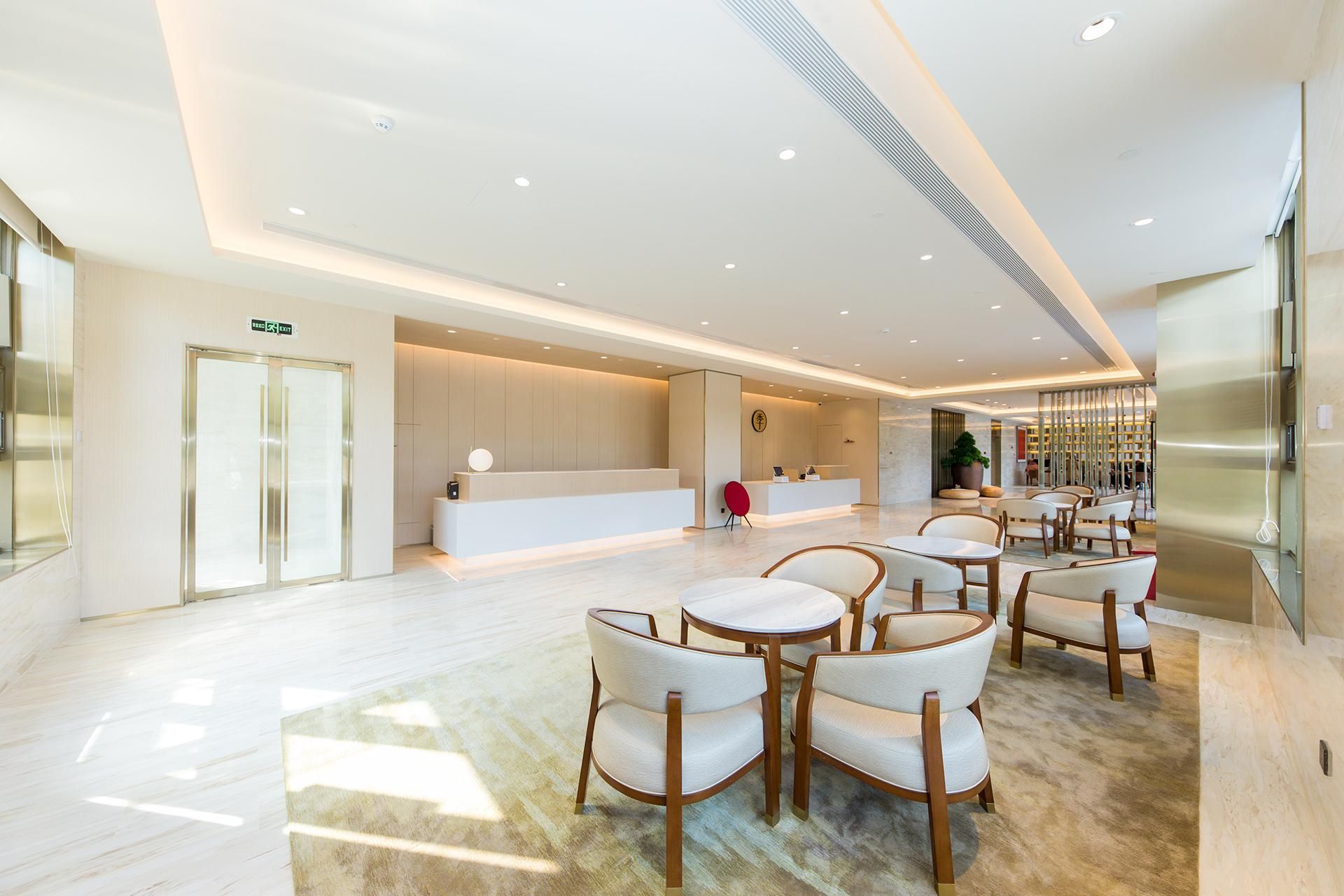 A spacious lobby with a reception desk, seating area, and a large plant.