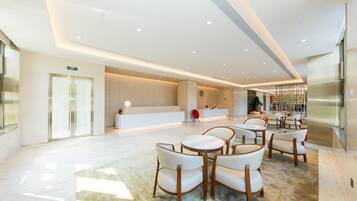 A spacious lobby with a reception desk, seating area, and a large plant.