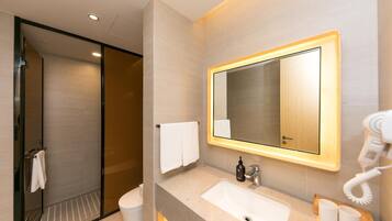 A modern bathroom with a large mirror, a sink, a toilet, and a hairdryer.