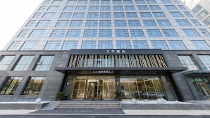 Un hôtel moderne, avec une façade en verre, une entrée imposante agrémentée d’une enseigne et une architecture symétrique.
