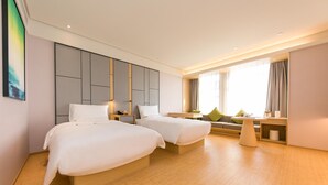Une chambre d’hôtel avec deux lits, un canapé, une petite table et une grande fenêtre avec des rideaux.
