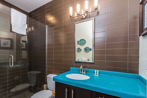 A bathroom with a blue countertop sink, a large mirror, and a wall-mounted light fixture. - Private Gated Beach & Heated Pool: Modern Siesta Key Cottage at Beach Club on Crescent Beach (Sarasota)