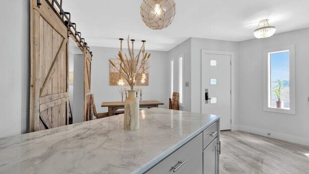 Una cocina moderna con encimera de mármol, puerta corrediza de madera y comedor con mesa y sillas.