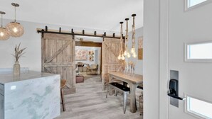 Una cocina moderna con encimera de mármol, puerta de madera estilo granero y lámparas colgantes.