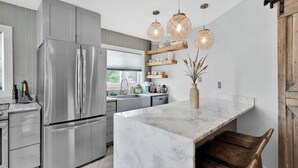 Una cocina moderna con una isla grande, electrodomésticos de acero inoxidable y detalles de madera.