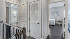Un couloir avec un escalier menant à une chambre à coucher où se trouvent un lit et une chaise.