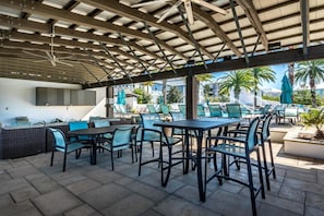 Un patio al aire libre con arreglos de asientos, piscina y una zona cubierta con una parrilla.